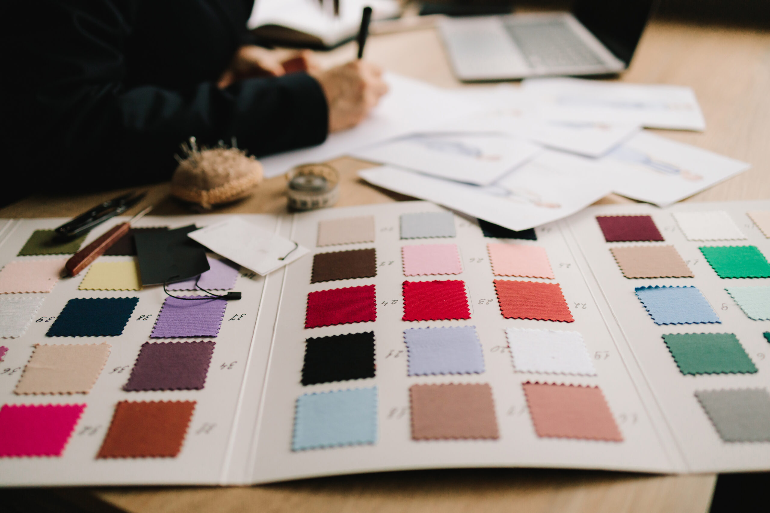 Designer plans dress designs on paper, preparing patterns and garment layouts.